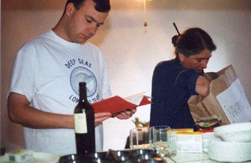 Ian reading a cookbook while Lori empties the bag